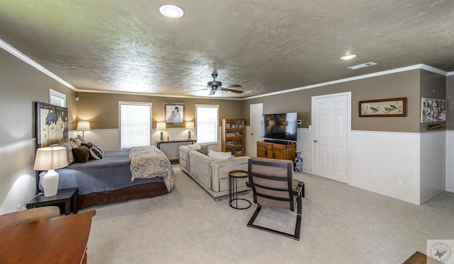 bedroom with light carpet, a textured ceiling, ceiling fan, and ornamental molding