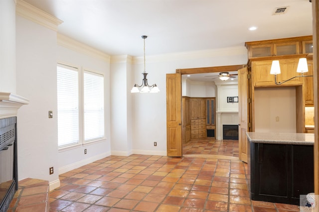 kitchen featuring ornamental molding, ceiling fan with notable chandelier, a tile fireplace, and plenty of natural light