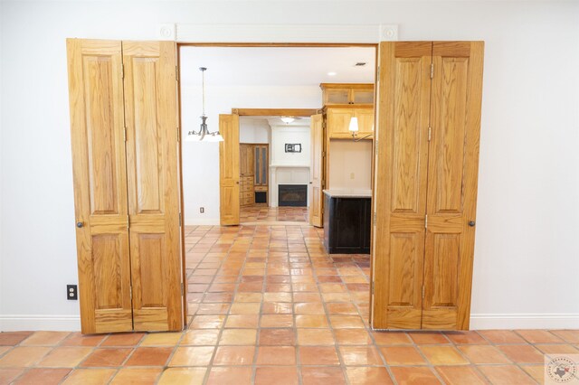 hallway with light tile patterned floors and a notable chandelier