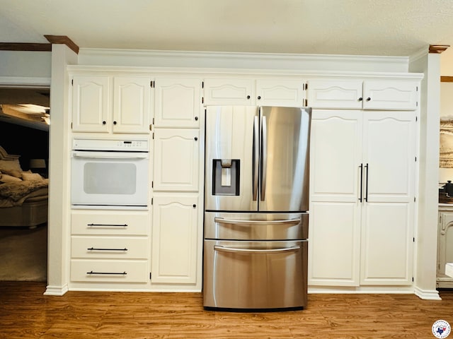 3705 Fm 2148 N, Texarkana, TX 75503 - kitchen with stainless steel fridge, oven, ornamental molding, light wood-style floors, and white cabinets