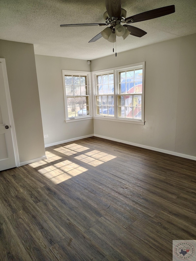 spare room with a textured ceiling, ceiling fan, dark wood-type flooring, and baseboards