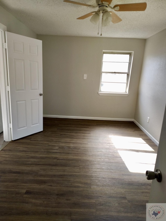 spare room with a ceiling fan, dark wood-style flooring, a textured ceiling, and baseboards