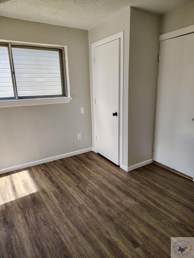 unfurnished bedroom featuring dark wood-type flooring and a textured ceiling