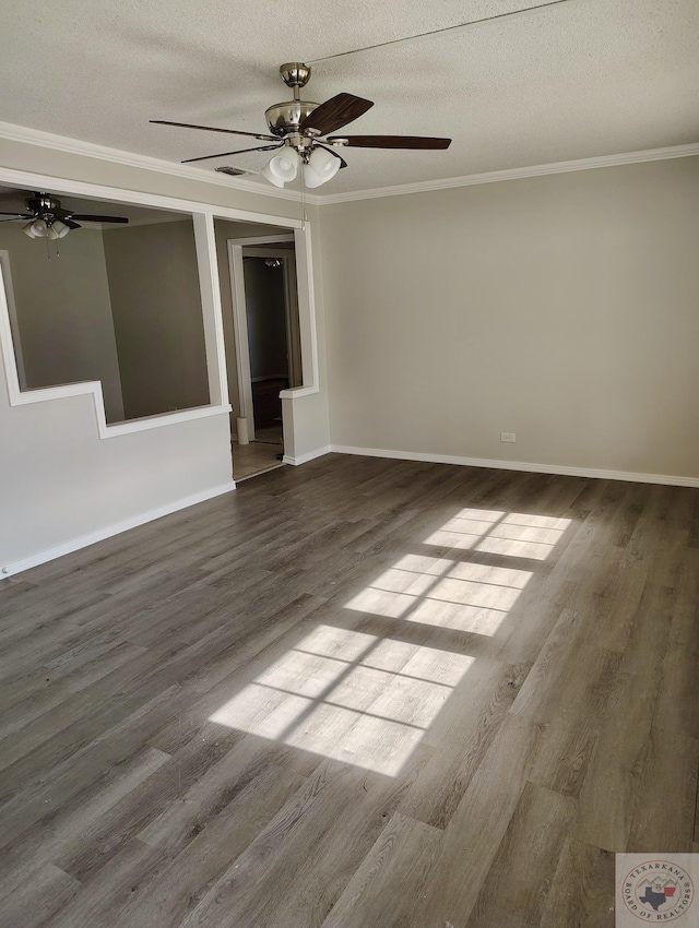 spare room featuring baseboards, a textured ceiling, ornamental molding, and wood finished floors