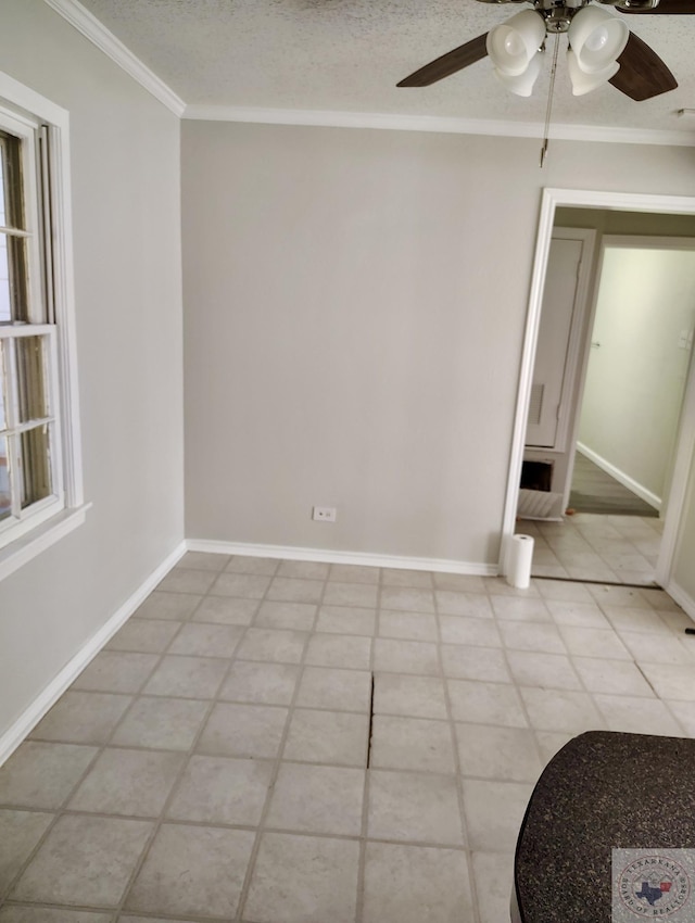 empty room featuring baseboards, ceiling fan, a textured ceiling, and crown molding