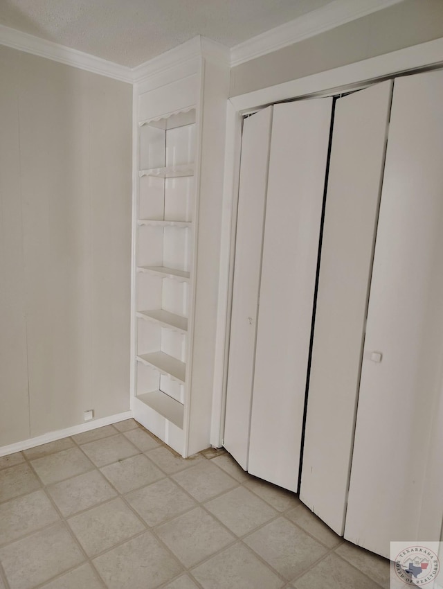 unfurnished bedroom featuring a textured ceiling, a closet, crown molding, and light tile patterned flooring