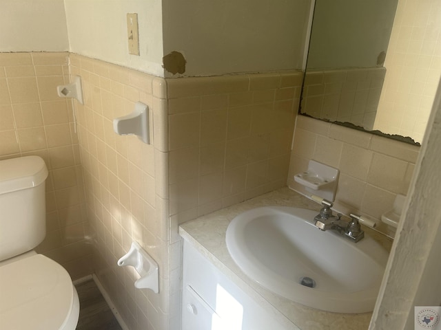 bathroom with toilet, decorative backsplash, vanity, and tile walls