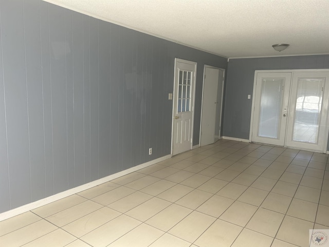 empty room featuring french doors, light tile patterned floors, and a textured ceiling