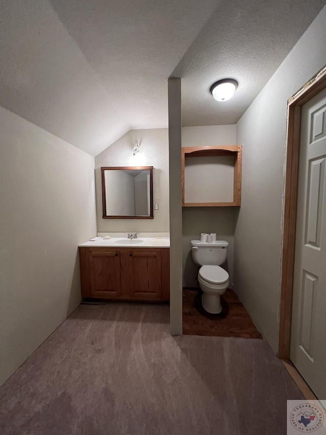 bathroom featuring a textured ceiling, toilet, vaulted ceiling, and vanity