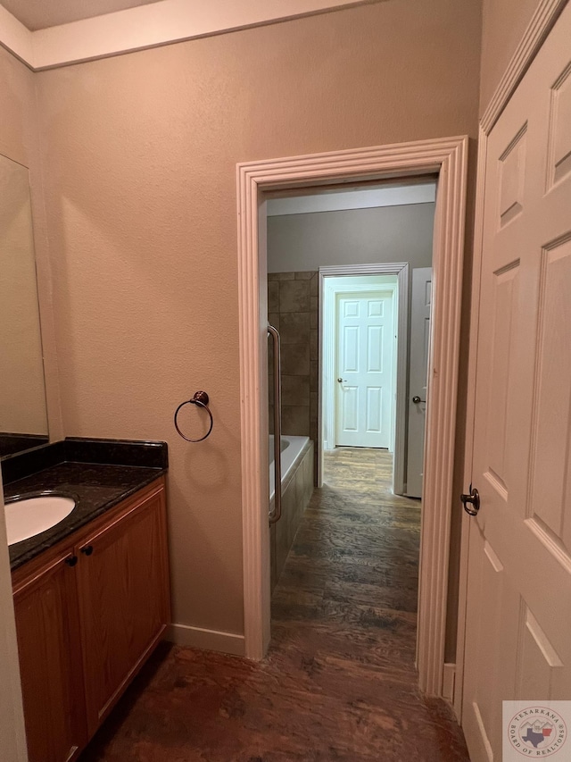 bathroom with hardwood / wood-style floors, tiled shower / bath, and vanity