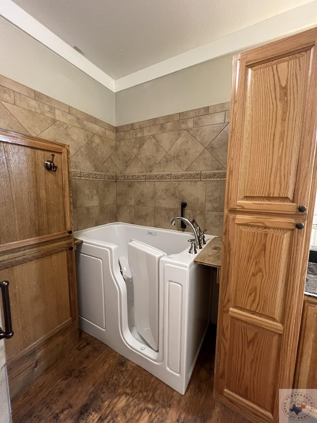 bathroom with hardwood / wood-style flooring, tile walls, and a tub