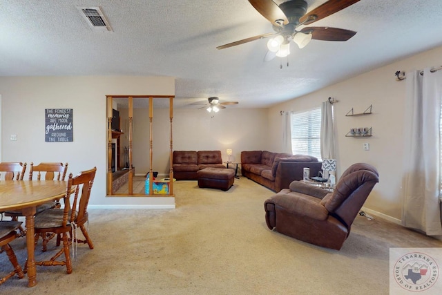 living area with baseboards, visible vents, a textured ceiling, and carpet flooring