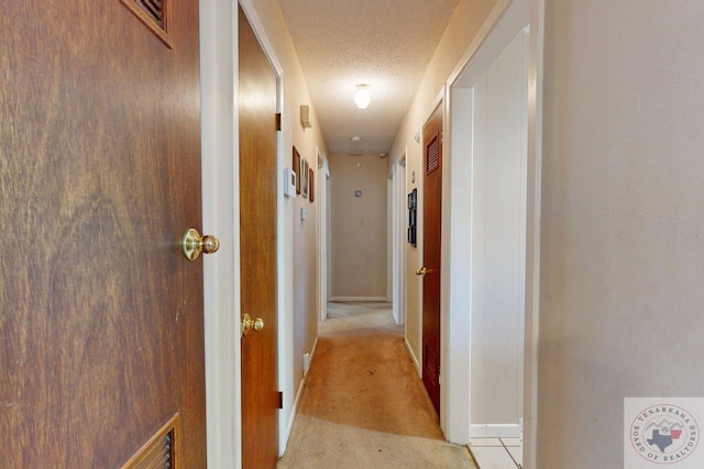 corridor featuring light carpet and a textured ceiling