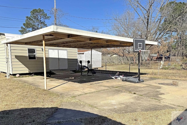 exterior space with concrete driveway, fence, and a detached carport