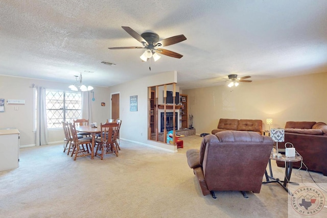 living area featuring light colored carpet, a textured ceiling, baseboards, and ceiling fan with notable chandelier