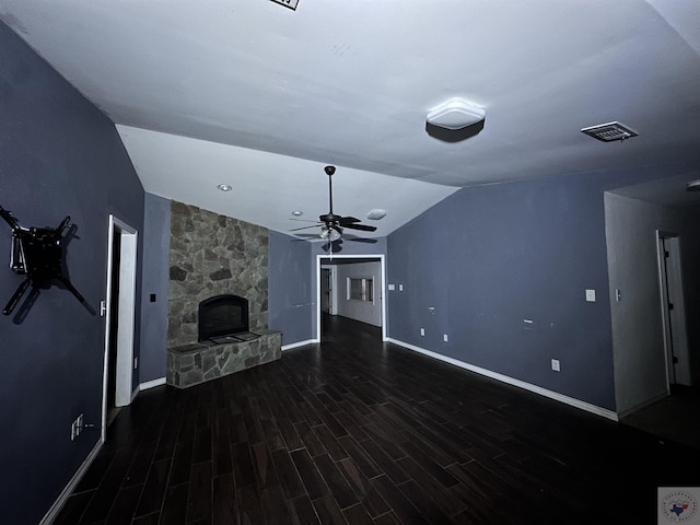 unfurnished living room with vaulted ceiling, a stone fireplace, ceiling fan, and dark hardwood / wood-style flooring