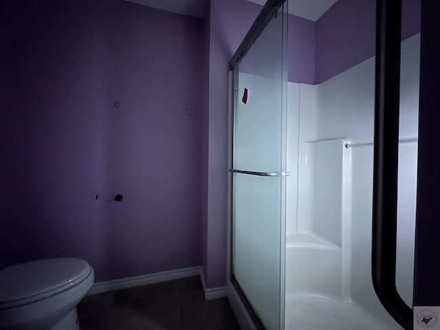 bathroom featuring a shower with door and toilet