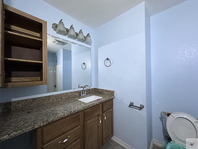 bathroom with toilet, vanity, and tile patterned flooring