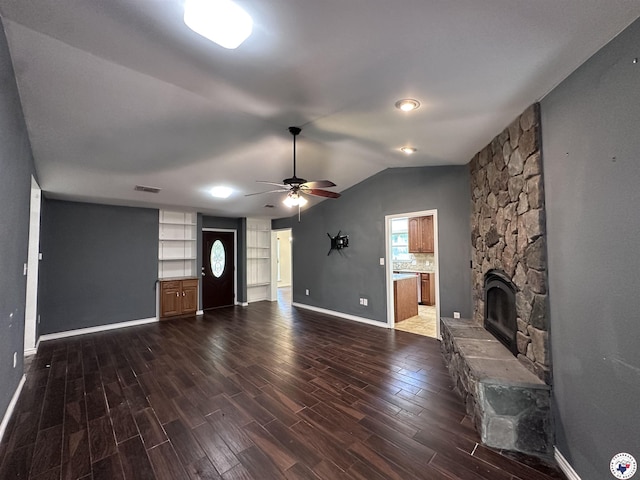 5611 Larry Dr, Texarkana, TX 75503 - unfurnished living room featuring baseboards, vaulted ceiling, a stone fireplace, a ceiling fan, and dark wood-type flooring