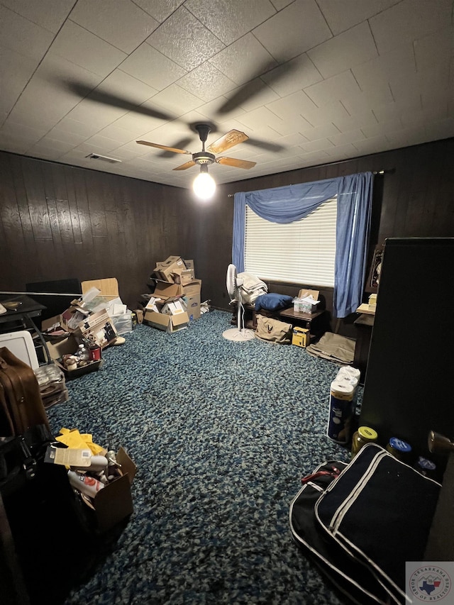 interior space featuring ceiling fan, carpet, and wood walls