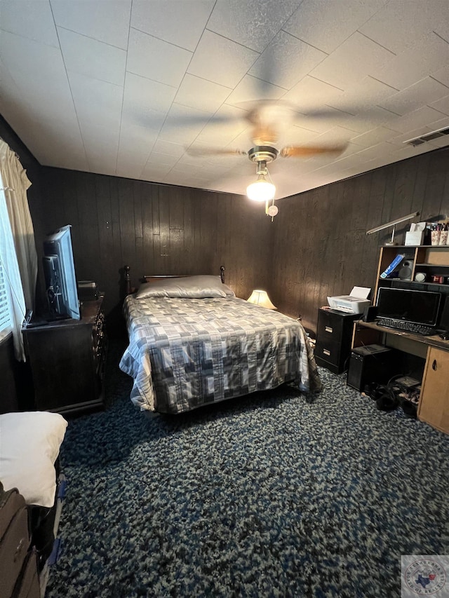 bedroom featuring wooden walls, carpet flooring, and ceiling fan