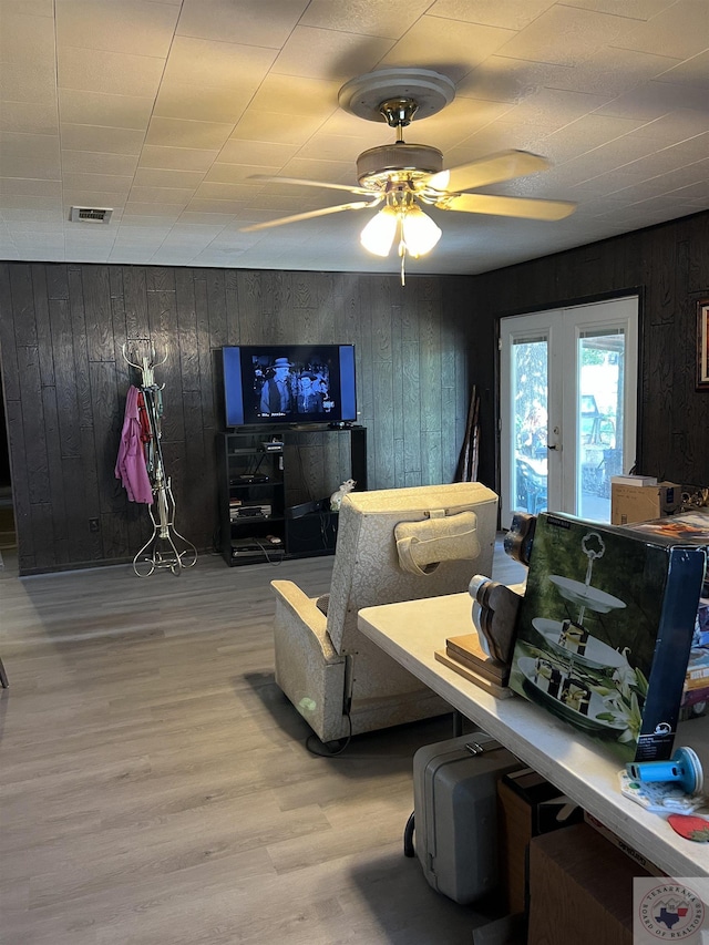 interior space featuring ceiling fan, hardwood / wood-style flooring, french doors, and wooden walls