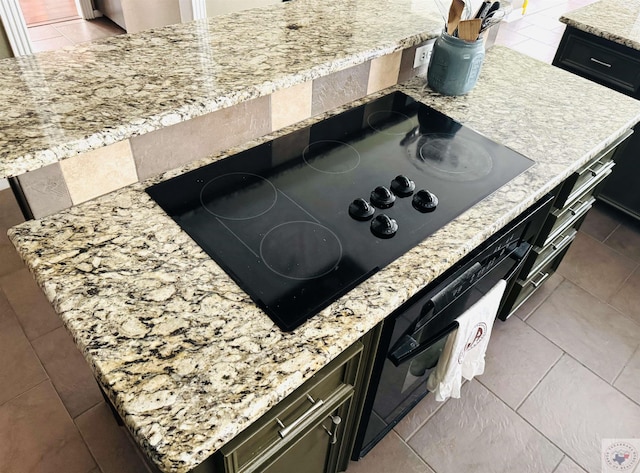 kitchen with light stone counters, tile patterned floors, and black electric cooktop