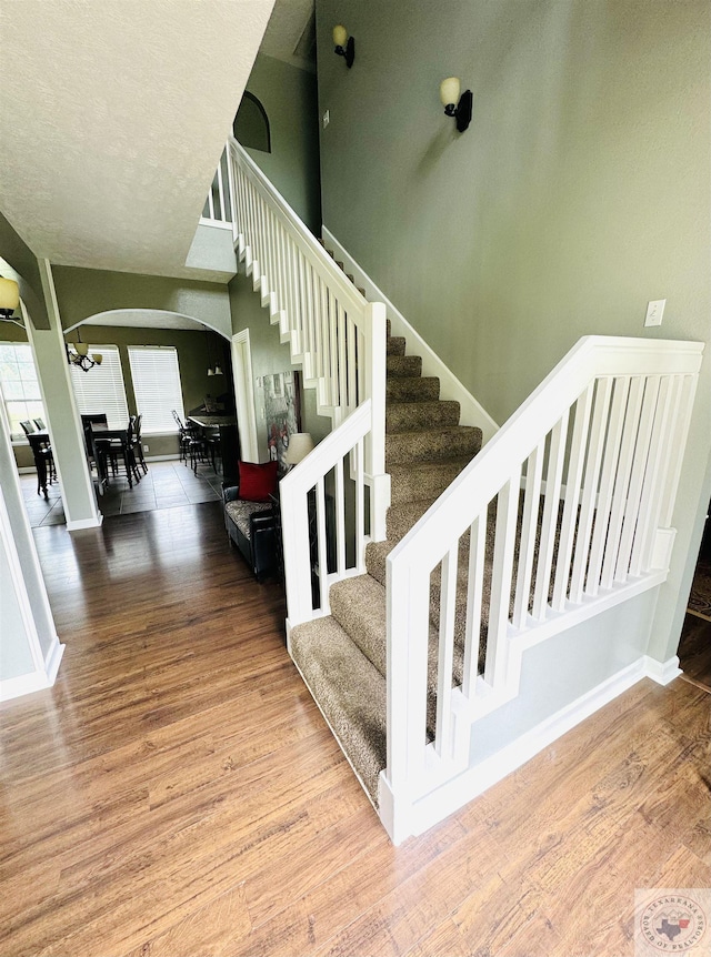 staircase with wood-type flooring and a textured ceiling