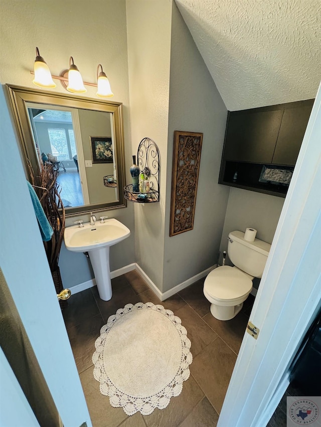 bathroom featuring a textured ceiling, lofted ceiling, tile patterned floors, sink, and toilet