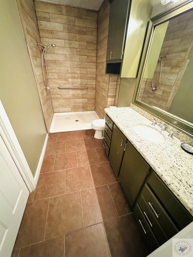 bathroom featuring tile patterned floors, toilet, vanity, and a tile shower