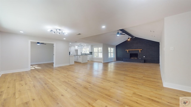 unfurnished living room with light hardwood / wood-style flooring, ceiling fan, a brick fireplace, vaulted ceiling with beams, and brick wall