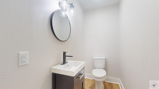 bathroom with wood-type flooring, toilet, and vanity