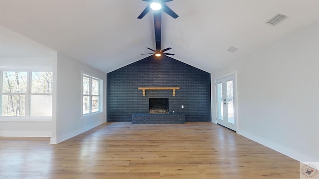 unfurnished living room with a fireplace, light wood-type flooring, lofted ceiling with beams, and ceiling fan