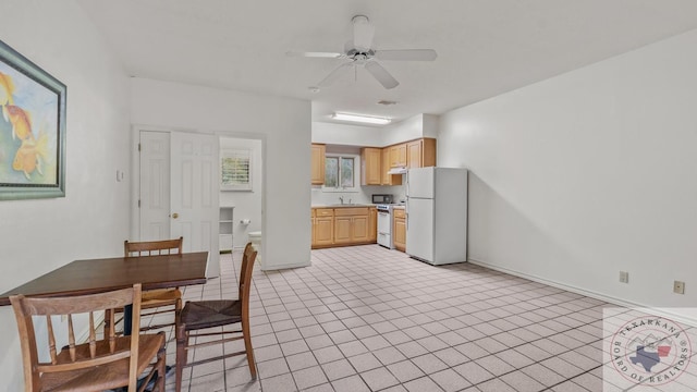 kitchen with white appliances, baseboards, light countertops, light brown cabinets, and a sink