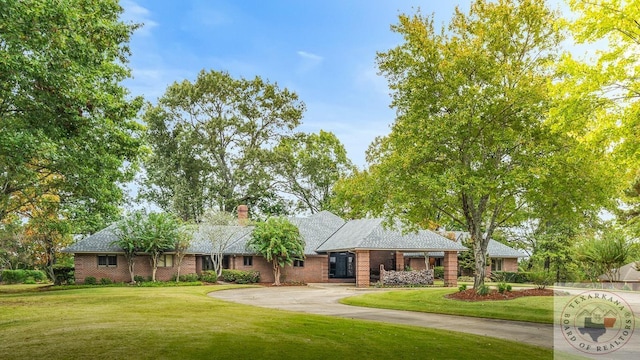 ranch-style home with concrete driveway, a front lawn, and brick siding