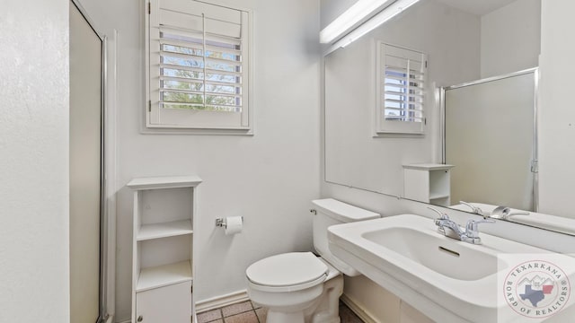 bathroom featuring a sink, a shower stall, toilet, and a healthy amount of sunlight