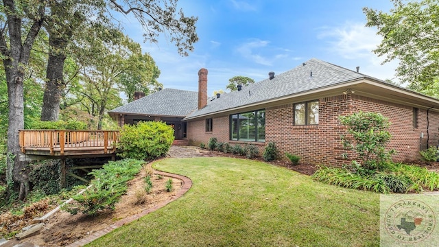 rear view of house with a wooden deck, a lawn, and brick siding