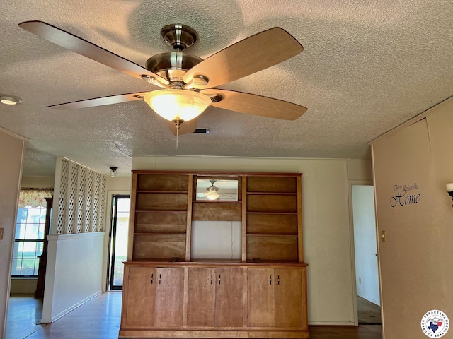 unfurnished living room featuring a textured ceiling, ceiling fan, wood finished floors, and baseboards