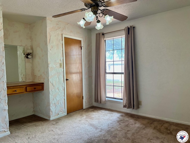 unfurnished bedroom featuring a textured ceiling, multiple windows, carpet floors, and baseboards