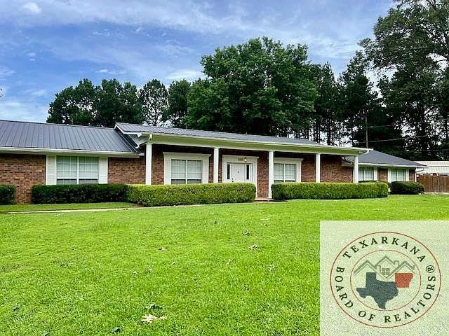 single story home with metal roof, brick siding, and a front lawn