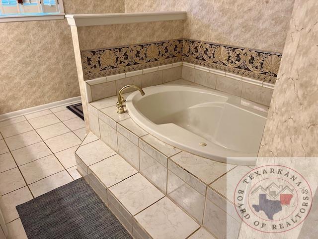 full bathroom with tile patterned floors, wallpapered walls, a bath, and baseboards