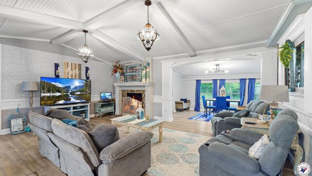 525 Longhorn Rd, Maud, TX 75567 - living room with a chandelier, wood finished floors, wainscoting, a warm lit fireplace, and brick wall