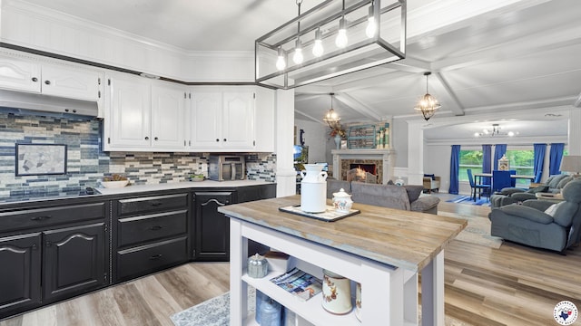 525 Longhorn Rd, Maud, TX 75567 - kitchen featuring white cabinetry, dark cabinets, light wood finished floors, a chandelier, and ornamental molding