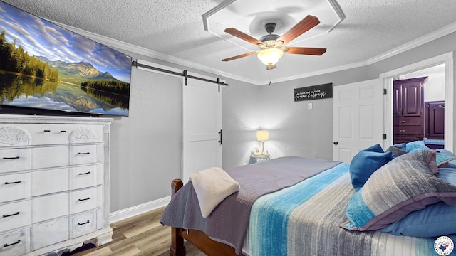 525 Longhorn Rd, Maud, TX 75567 - bedroom with wood finished floors, a barn door, a textured ceiling, ornamental molding, and a ceiling fan