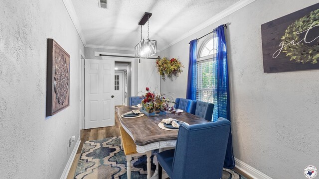 525 Longhorn Rd, Maud, TX 75567 - dining space featuring a barn door, a textured wall, crown molding, wood finished floors, and a textured ceiling