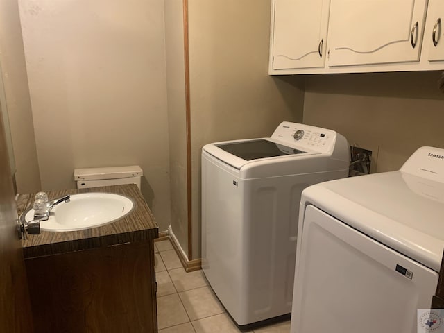 clothes washing area with sink, washing machine and dryer, and light tile patterned flooring