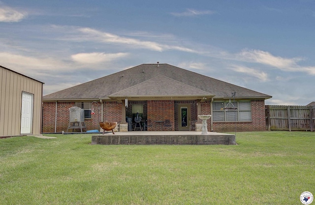 rear view of house featuring brick siding, a lawn, fence, and a patio area