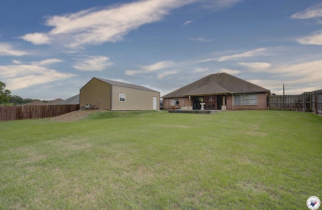 back of house with a lawn, an outdoor structure, a fenced backyard, and brick siding