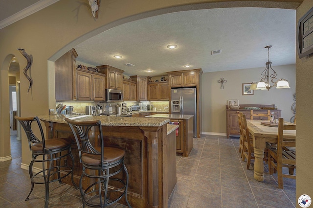 kitchen with appliances with stainless steel finishes, arched walkways, a peninsula, baseboards, and visible vents