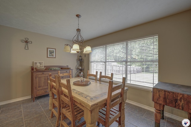 dining area featuring an inviting chandelier, baseboards, dark tile patterned floors, and a wealth of natural light